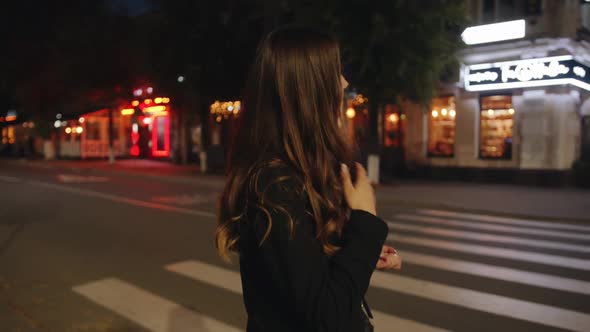 Trendy Young Girl Goes Along a Pedestrian Crossing in the Evening and Heads to a Summer Cafe alt