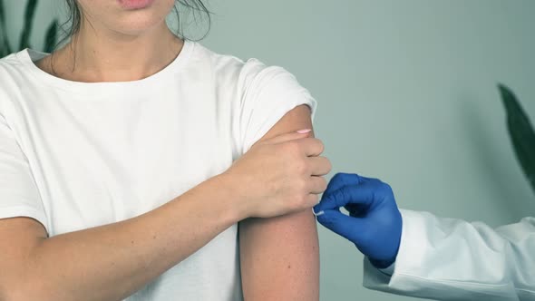 Professional Male Doctor in Medical Gloves Giving Flu Vaccine Injection to Female Patient alt