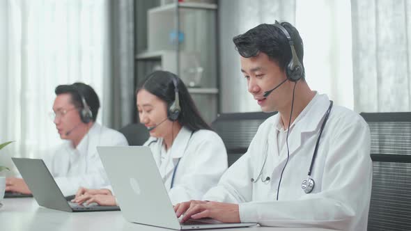 Three Asian Doctors With Stethoscopes Wearing Headsets Working As Call Centre Agents alt