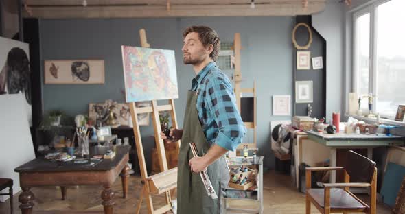 Male Artist Holding Brushes in Studio Portrait