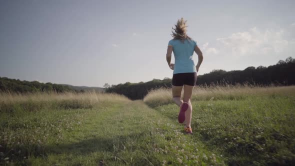 Slow Motion Following Woman Jogging Through High Grass in Summer