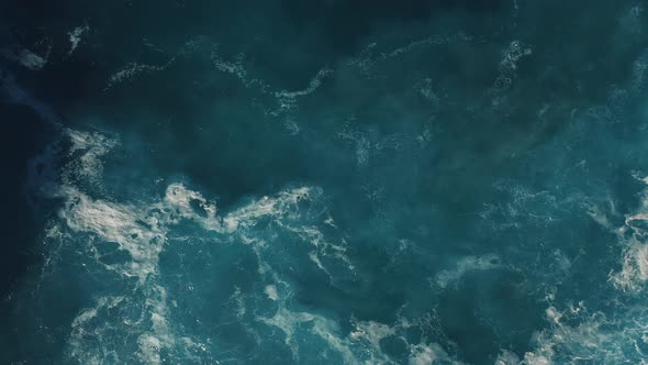 Top down view of crushing waves; blue water, thick seafoam, natural abstract pattern, sea texture