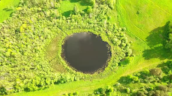Aerial Flight From Top Bottom Over an Small Lake with Perfectly Round Shape alt