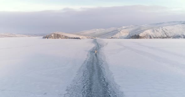Drone Pursuing a Small Boat Icebreaker Moving on the Surface of a Frozen Lake Aerial View Flight alt