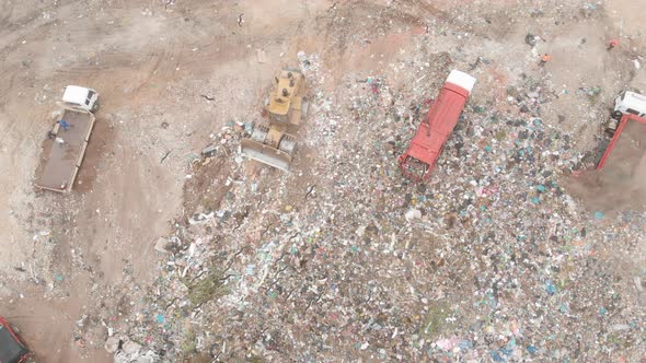Vehicles clearing rubbish piled on a landfill full of trash alt