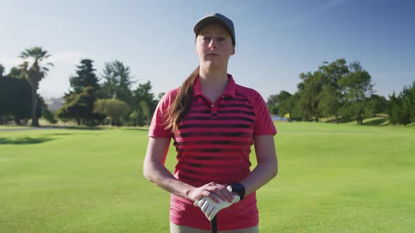 Portrait of female caucasian golf player smiling while standing at golf course alt