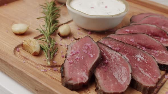 Grilled Rare Medium Beef Meat with Garlic and Rosemary in a Woden Plate alt