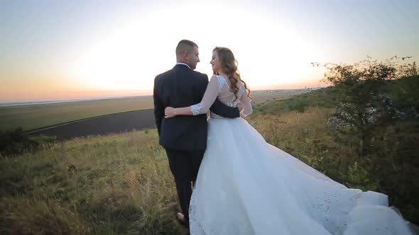 Bride and Groom Walking on the Grass Field in Love with Her Wedding Day alt