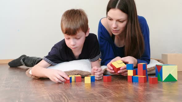 Mom and Son Playing Together Wooden Colored Education Toy Blocks Lying on the Floor.
