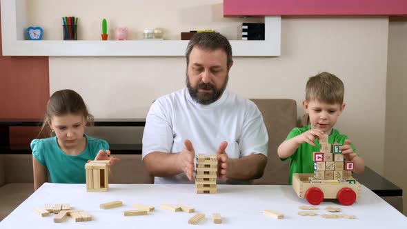 Bearded dad and children play with wooden blocks and toys. Social distancing
