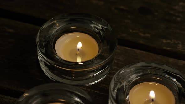 Tea candles with flaming wicks on a wooden background - CANDLES 025 alt