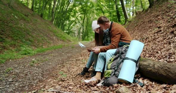 Tourists with Map Resting Sitting in Forest