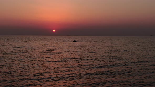 Drone flying around the lonely boat in the sea with a fishing man at sunrise. Amazing rising sun