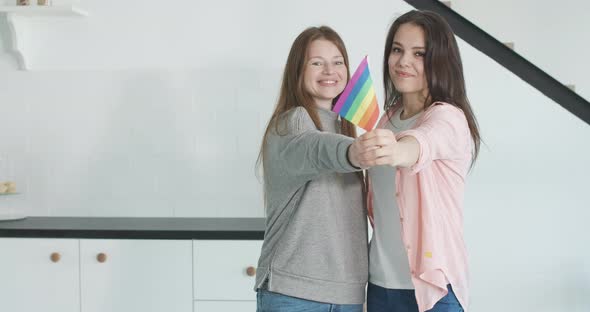 Portrait of Happy Homosexual Couple Stretching LGBT Rainbow Flag To Camera. Young Cheerful Charming alt