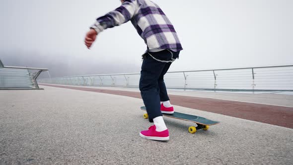 Close Portrait of Young Professional Skater Guy Performing Board Flip on City Bridge on Foggy alt