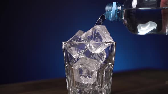 Close Up Transparent Clean Drinking Water Is Poured Into Glass with Cube Ice. The Glass Is Spinning alt