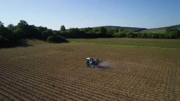Aerial view of tractor spraying fertilizer on field at spring. Beautiful landscape in the background