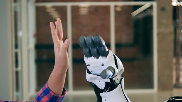 Close Up Shot of a Futuristic Robot Touching Hands with a Kid alt