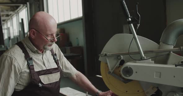 The Engineer in Glasses Examines and Touches the Lever of Machine on a Factory alt