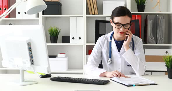 Doctor Talking on Phone and Looking in Documents