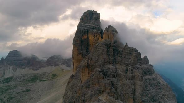 Aerial view across clouds over majestic Tre Cime mountain peak rock formation scenery in South Tyrol alt