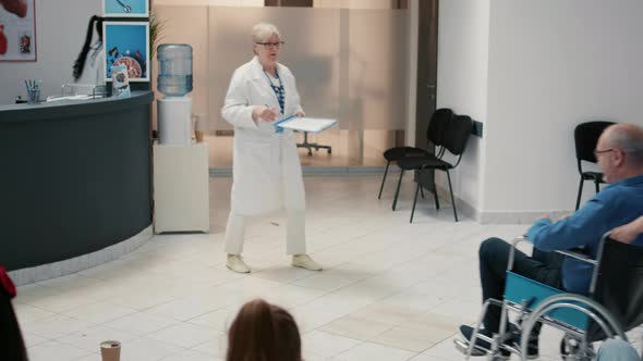 Senior Physician Talking to Retired Man with Disability at Hospital Reception alt