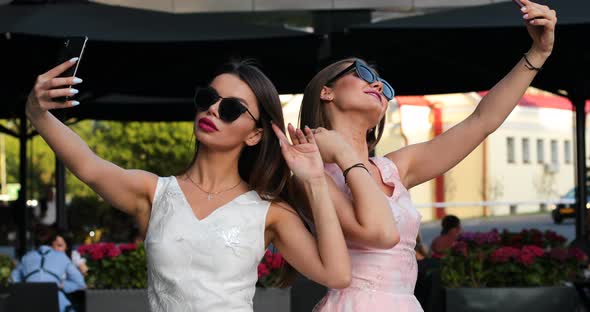 Two Fashionable Woman with Red Lips Making Self Portrait at Smart Phones