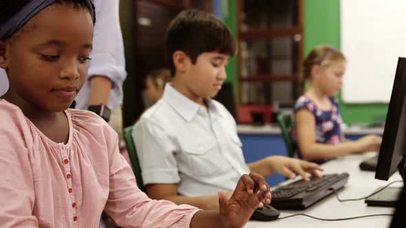 Teacher assisting school kids on personal computer in classroom alt
