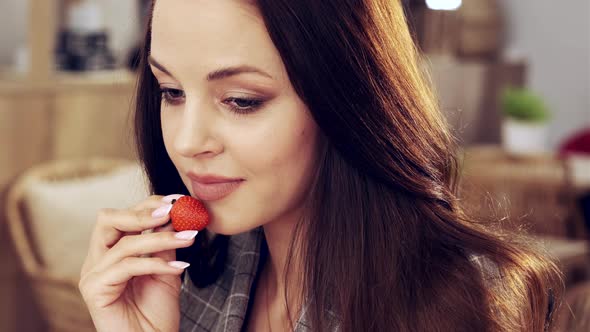 a Woman is Sitting in a Cafe and Eating Strawberries