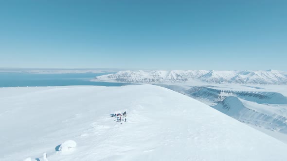 Team of hikers reaching snowy mountain top in majestic landscape of Svalbard alt