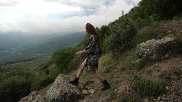 A Girl Looks at the Magnificent Landscape of Nature From the Edge of the Cliff alt