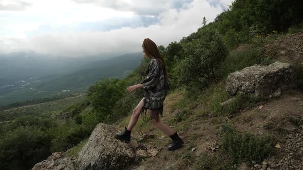 A Girl Looks at the Magnificent Landscape of Nature From the Edge of the Cliff