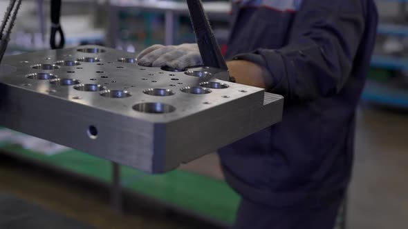 Worker Is Rising Big Heavy Metal Detail By Ropes in a Workshop and Removing It Over Table alt