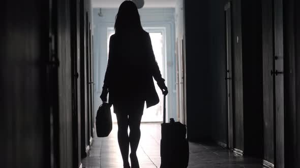 Silhouette of Businesswoman Going with Luggage in Hotel