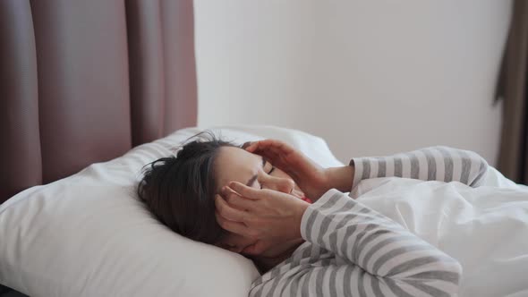 Young asian woman suffering from head ache in the bedroom after wake up in the morning