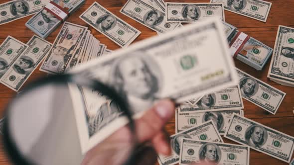 One Hundred Dollars Inspecting Under Magnifying Glass on Money Background alt