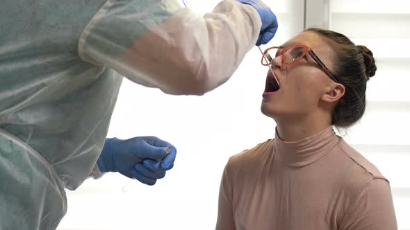 Lab Technician in a Protective Suit Takes a Swab From an Female Patient for Coronavirus. alt
