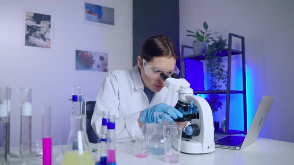 Young Woman Chemist is Using Modern Microscope for Examining Samples alt