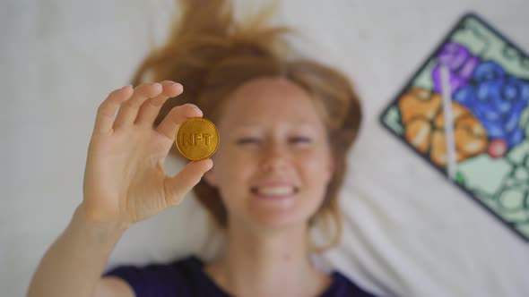 Woman Digital Artist Contemporary Painter Holds an NFT Coin in Her Hand alt