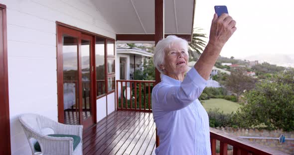 Woman taking selfie with mobile phone in balcony at home 4k