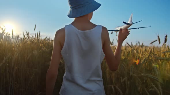 Boy in a Hat Playing with Airplane in a Golden Wheat Field Boy Dreams of Being a Pilot