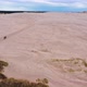 Aerial Wide Shot Of Tourists Walking on Sand Dunes Towards the Horizon - VideoHive Item for Sale