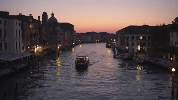 Wide tracking shot of boat cruising through Canal Grande at Twilight, Venice, Italy alt