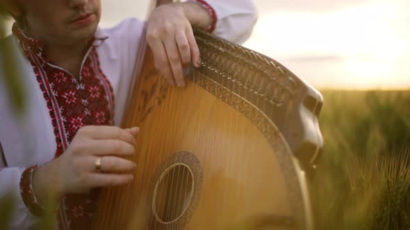 Close Up Shot of Bandurist Playing on Bandura Hands of Musician Pinch Strings on His Fold Instrument
