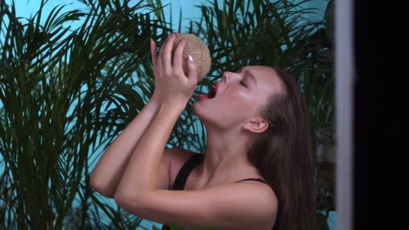 Woman in the Studio Tropics Drinks Water From a Coconut