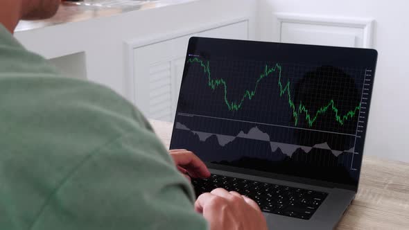 Over the Shoulder View of Male Trader Investor Works with Financial Charts Exchange Rates Stocks or alt