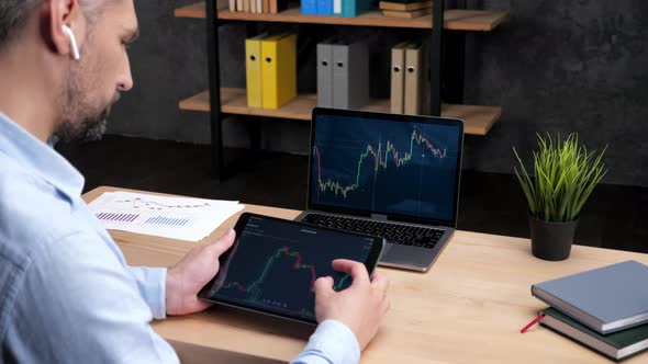 Man Broker Scrolling Tablet with Stock Exchange Chart Laptop with Stock Market alt