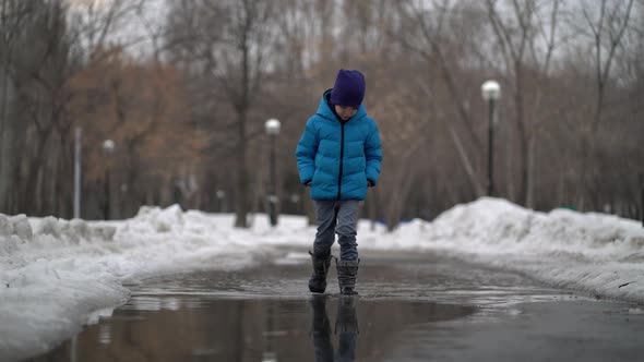 Boy Walking in a Puddle at Winter