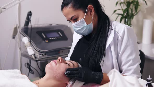 Professional Cosmetologist is Applying Face Cream and Making Face Massage for Young Woman with alt