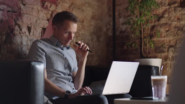 Thoughtful Serious Young Man Student Writer Sit at Home Office Desk with Laptop Thinking of alt